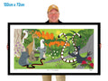 Man holding a large framed artwork of animals in a forest setting