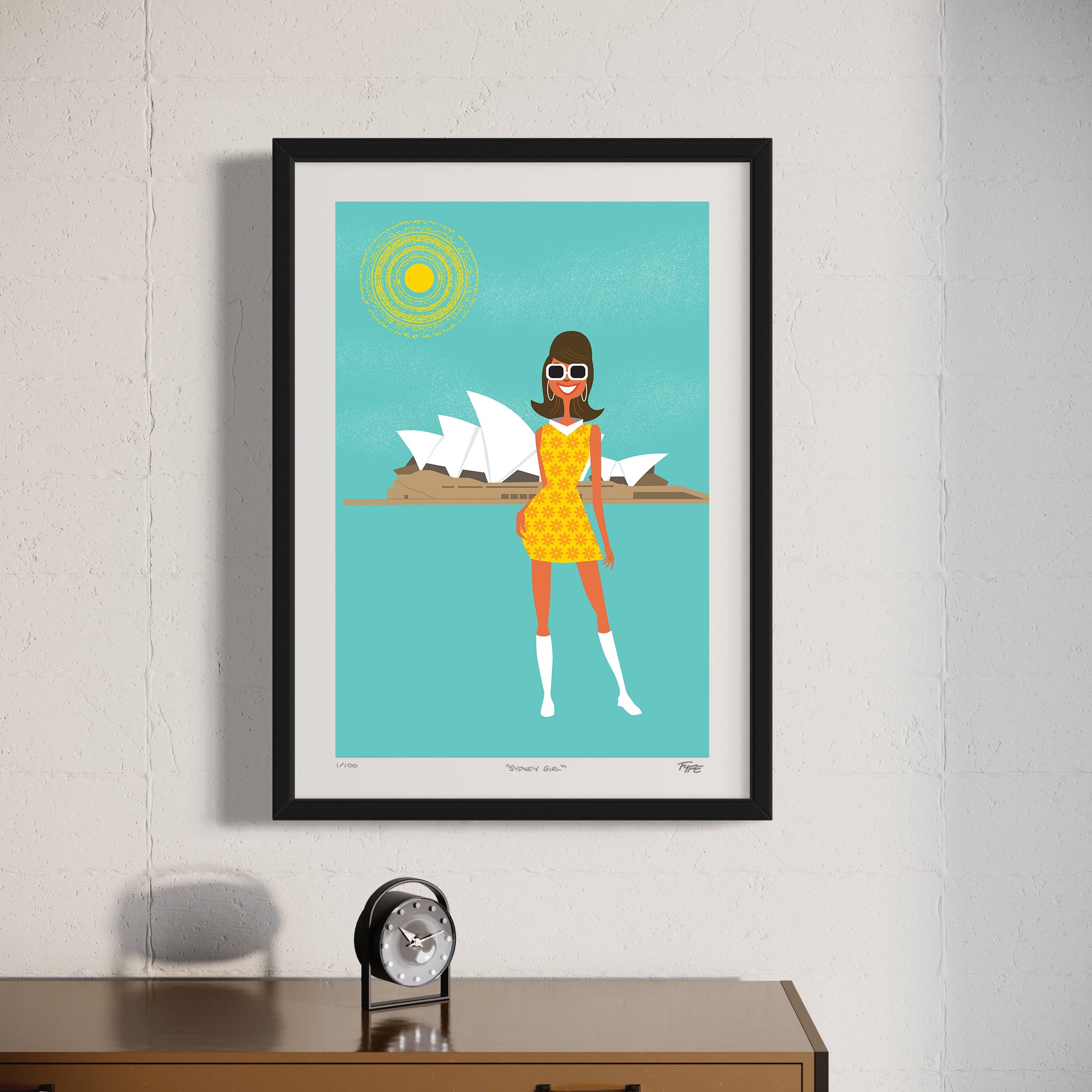 Framed artwork of a woman in a yellow dress with the Sydney Opera House in the background, on a white wall.