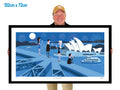 Person holding a framed artwork of the Sydney Opera House and Harbour Bridge.