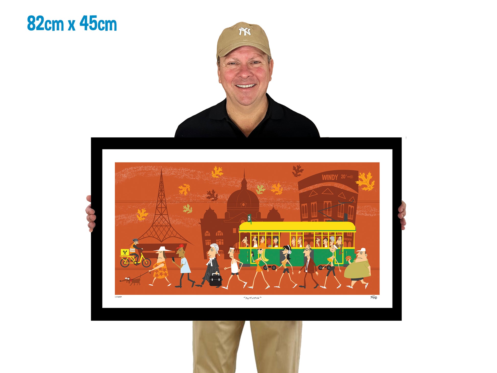 Man holding a framed artwork of a city scene with a tram and people on a white background