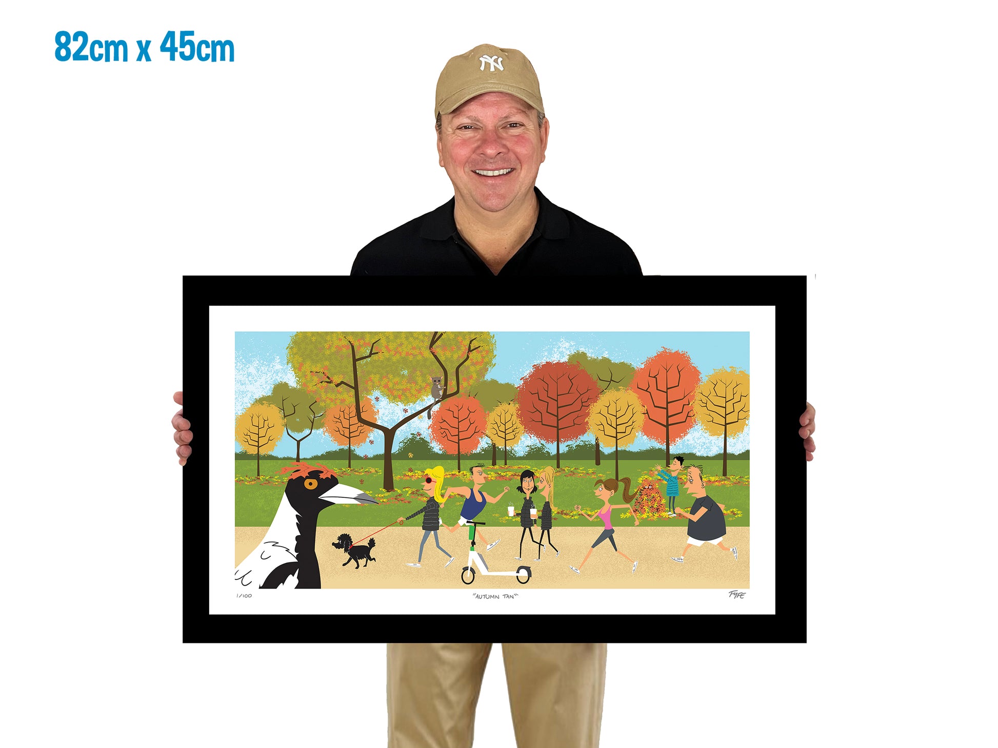Man holding a framed artwork of a park scene with people and trees.