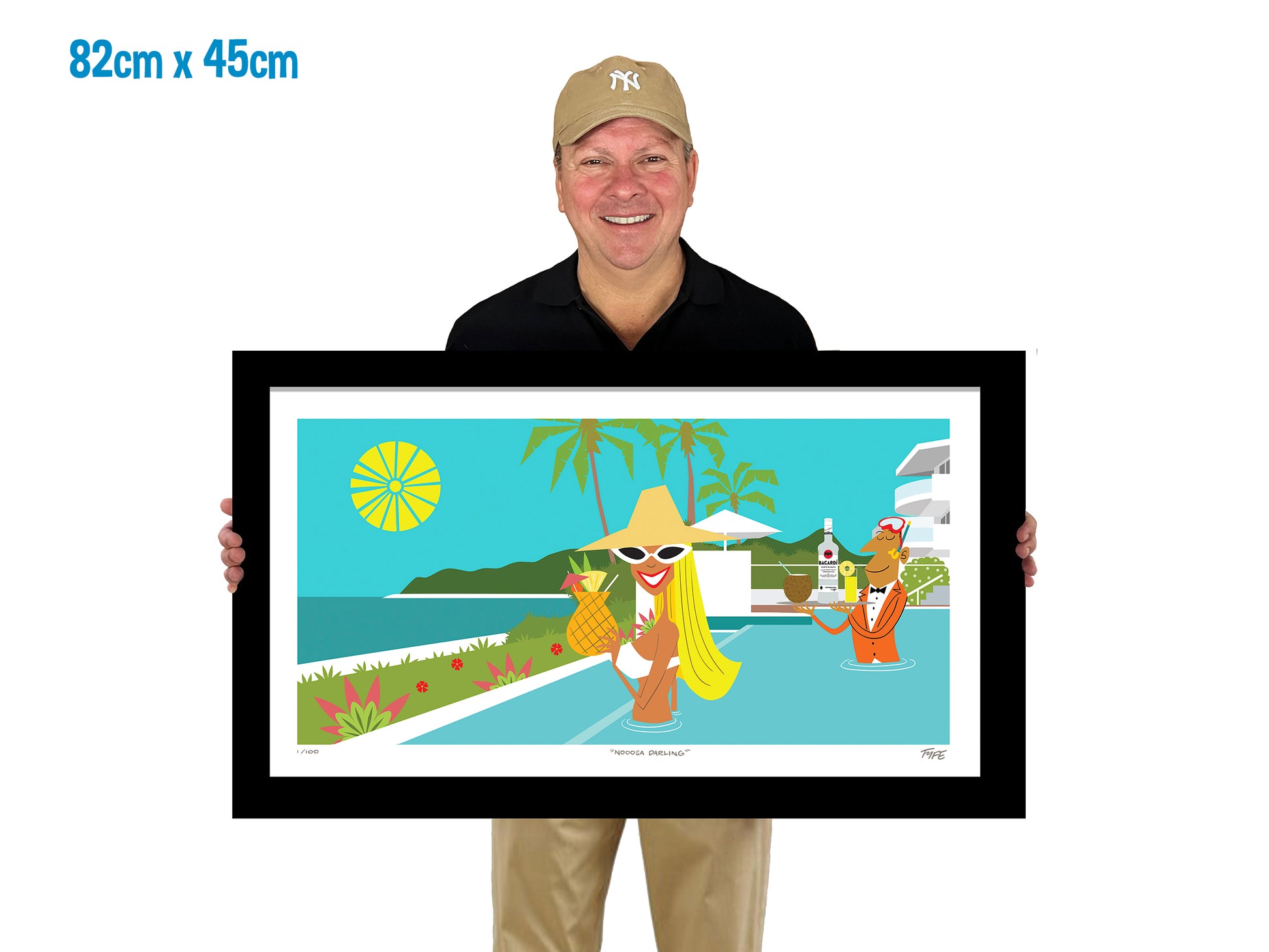 Man holding a framed artwork of a tropical scene with people by the pool.