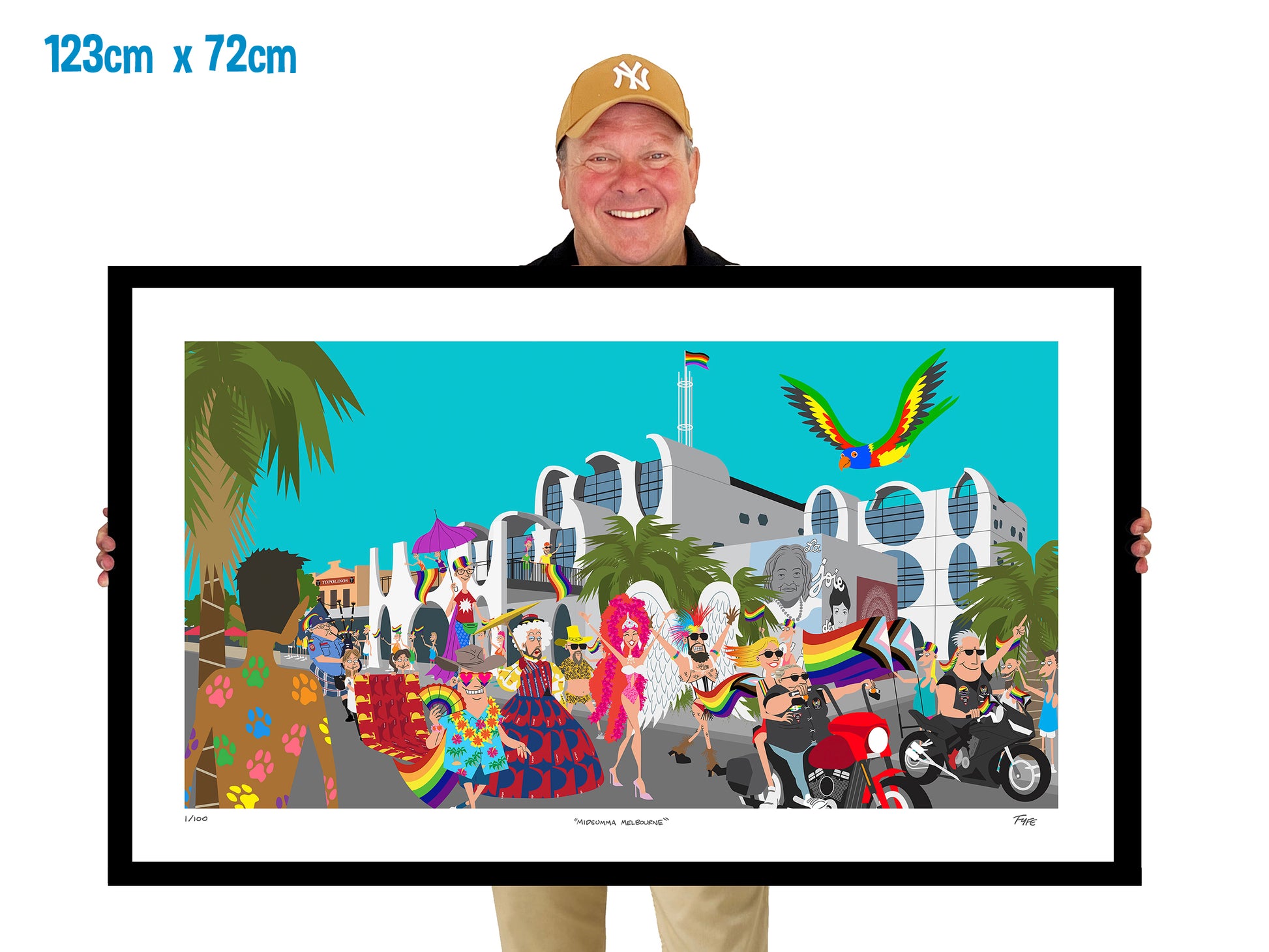 Person holding a large framed artwork of a colorful scene with people and buildings.