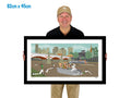 Man holding a framed artwork of a city scene with a river and bridge.