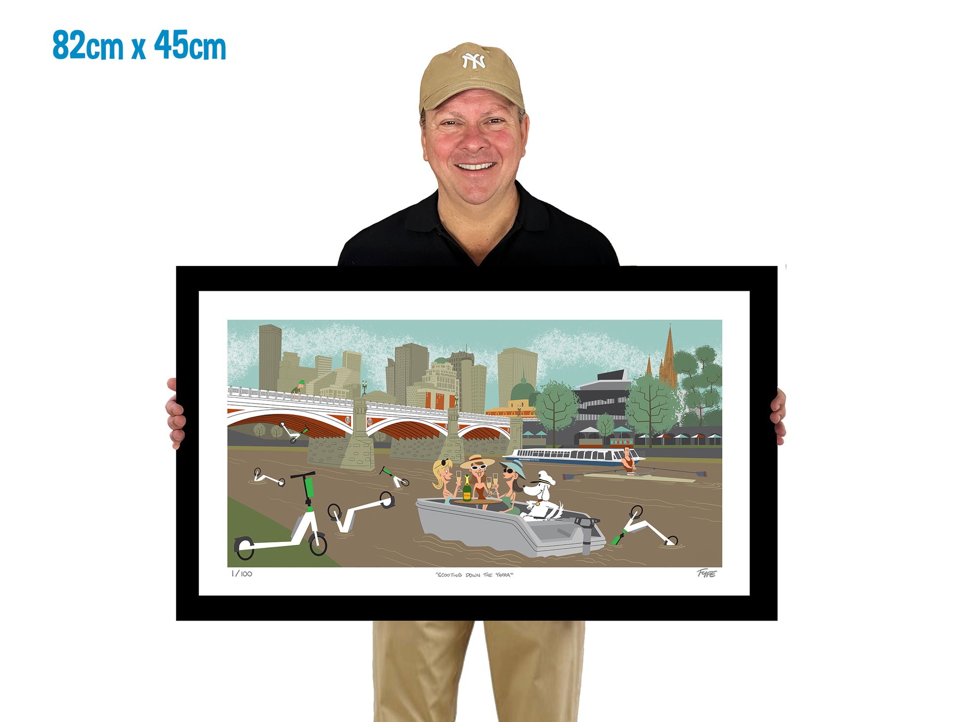 Man holding a framed artwork of a city scene with a river and bridge.