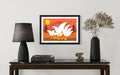 Framed artwork of two birds on an orange background above a table with decor items.