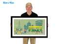 Man holding a framed illustration of a city scene with a green background