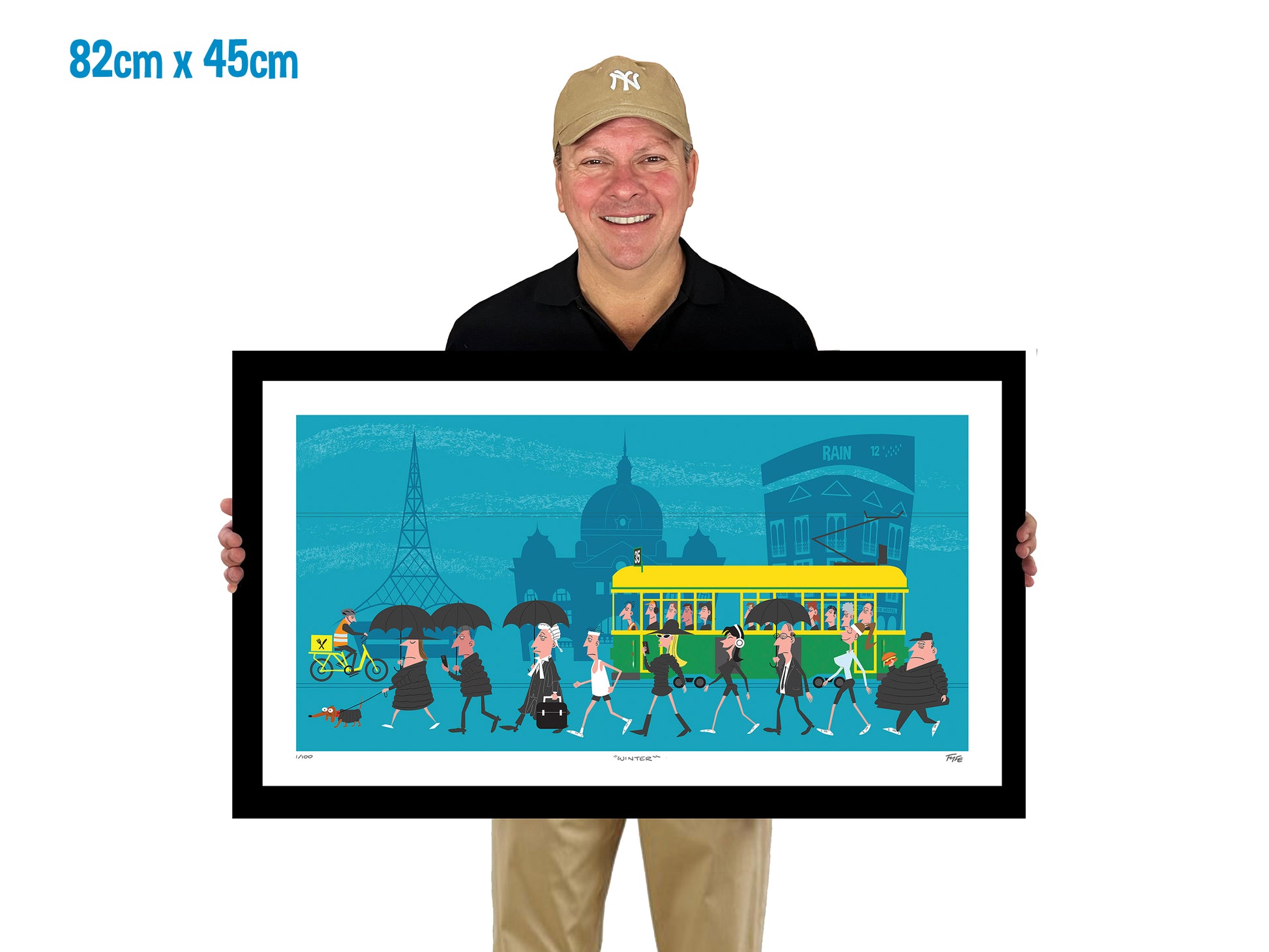 Man holding a framed artwork of a city scene with a bus and people on a white background